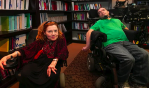 Photo of two motorized wheelchair users in a room with bookcases, Nichole Gladu with post-polio syndrome and Jean Truchon with cerebral palsy. (Photo by Ivanoh Demers/Radio Canada)